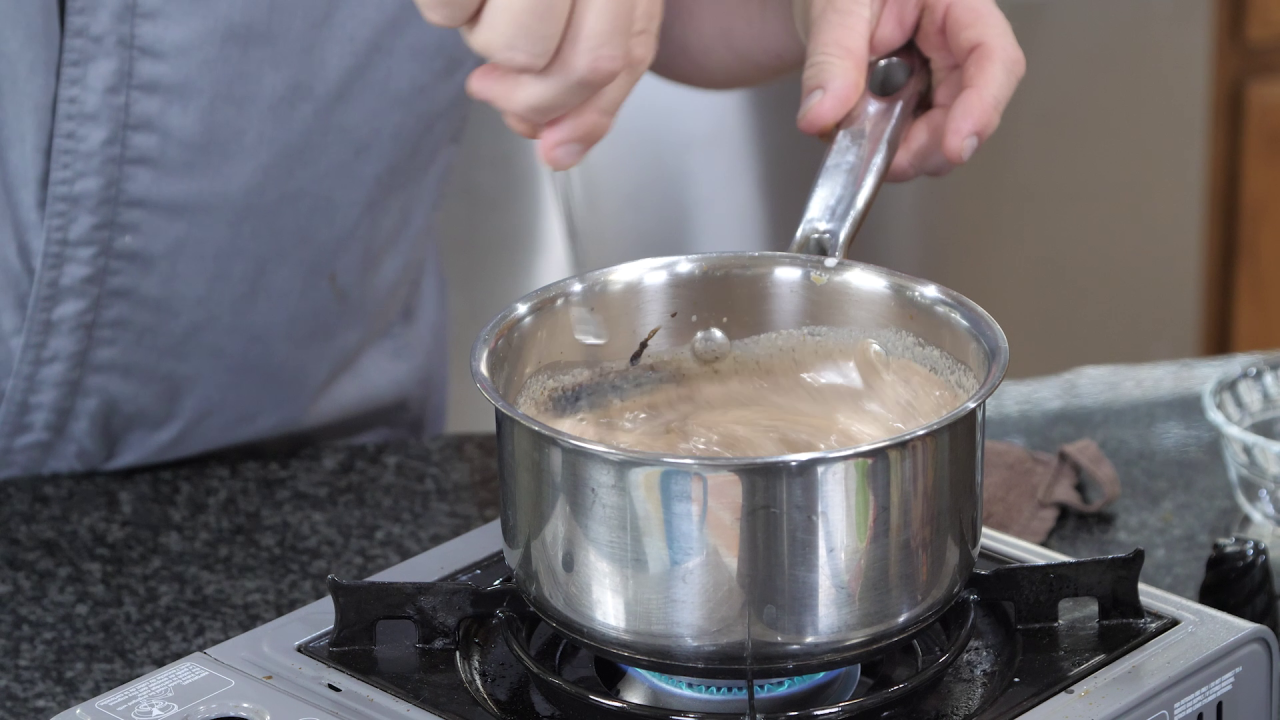 Chef Jeff whisks the Pumpkin Spice Hot Cocoa, still cooking in the small pot, in order to thicken it.