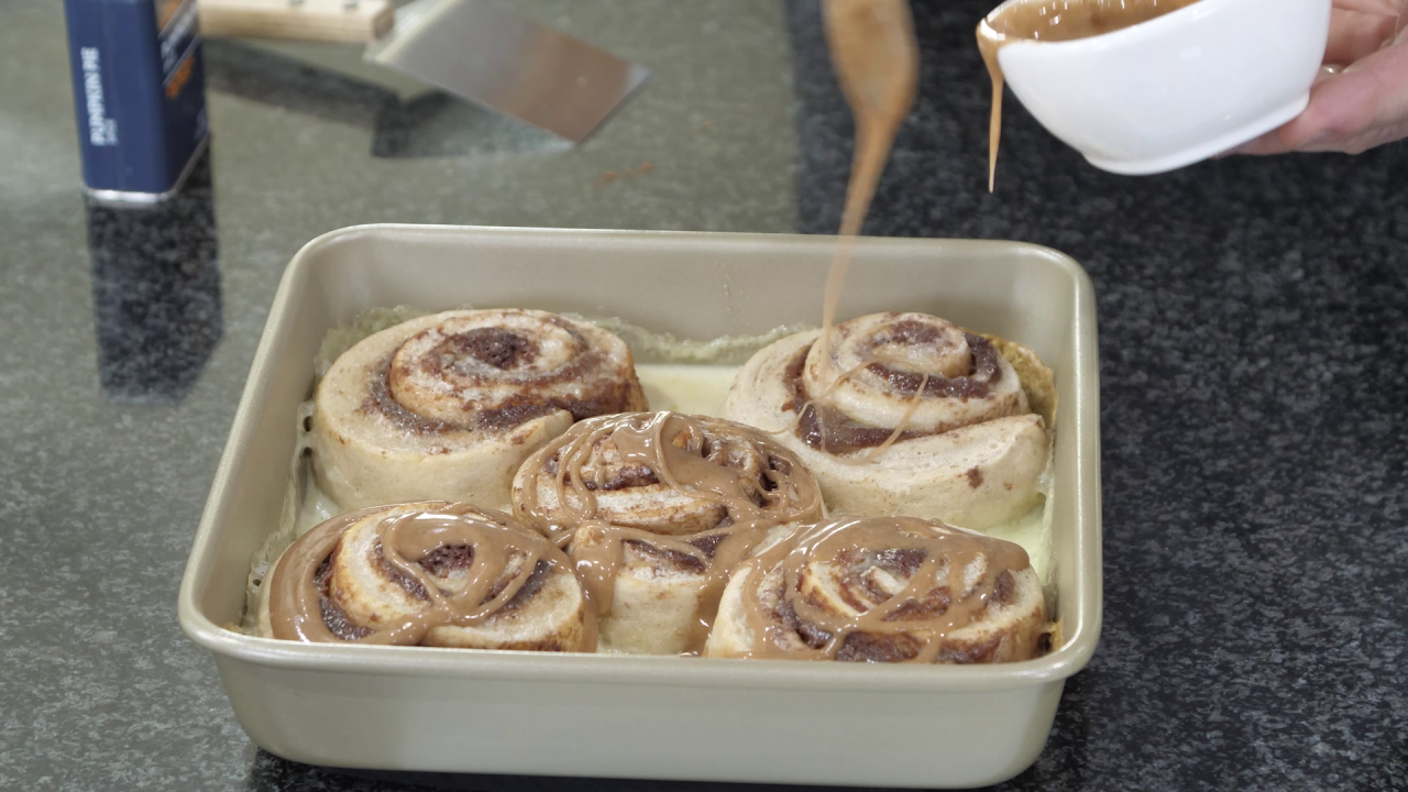 The freshly baked cinnamon rolls, still in the baking pan. Chef Jeff drizzles the frosting on top of them.